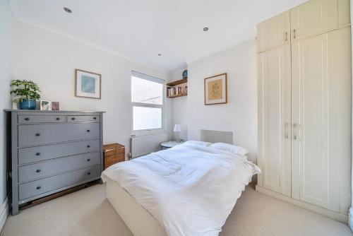 a bedroom with a white bed and a dresser at Entire Modern Apartment with Garden Near Underground Station in London