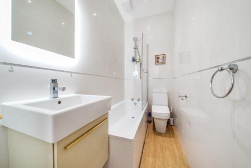 a white bathroom with a sink and a toilet at Entire Modern Apartment with Garden Near Underground Station in London