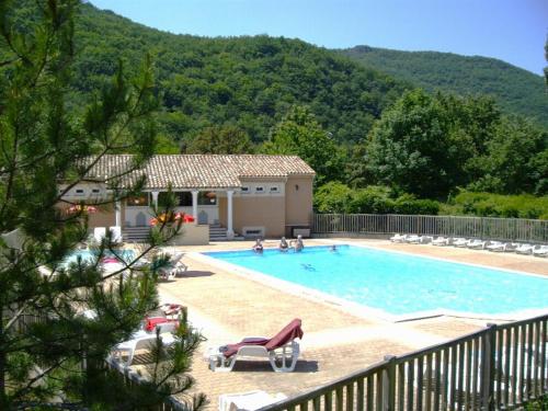 a swimming pool with chairs and a house at Camping Le Gallo Romain in Barbières