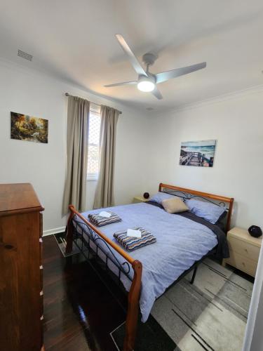 a bedroom with a bed with a ceiling fan at Bottlebrush Retreat Geraldton in Geraldton