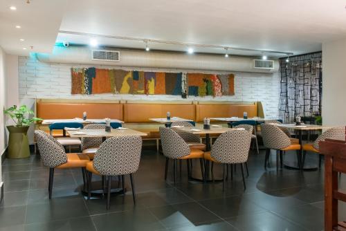 Un comedor con mesas y sillas de madera. en DoubleTree by Hilton Cape Town Upper Eastside, en Ciudad del Cabo