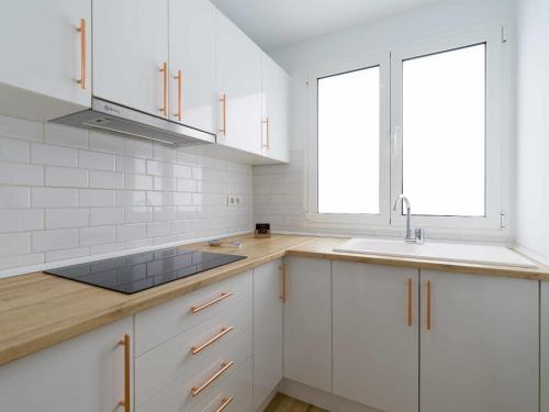 una cucina con armadi bianchi, lavandino e due finestre di Moguel Canarian Holiday 2º a Arguineguín