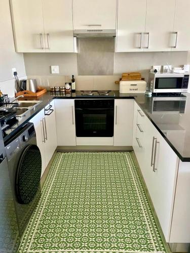 a kitchen with white cabinets and a dishwasher at SaltySky Penthouse in Gansbaai
