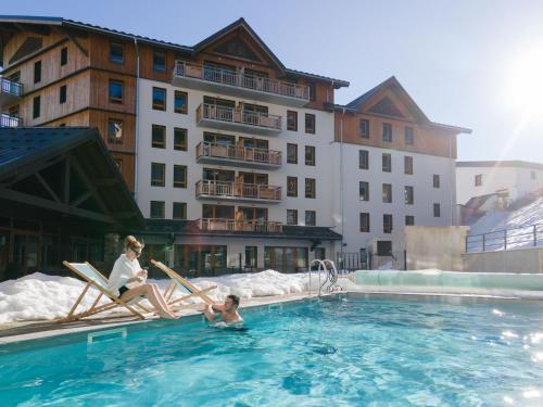 a woman and a child sitting in a pool at a hotel at Résidence Club MMV Les Clarines in Les Deux Alpes