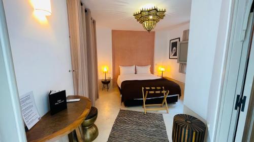 a hotel room with a bed and a table and a desk at Riad Dar Amazonia in Marrakech