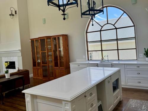 cocina con encimera blanca y ventana grande en Bergzicht Villa, en Swellendam