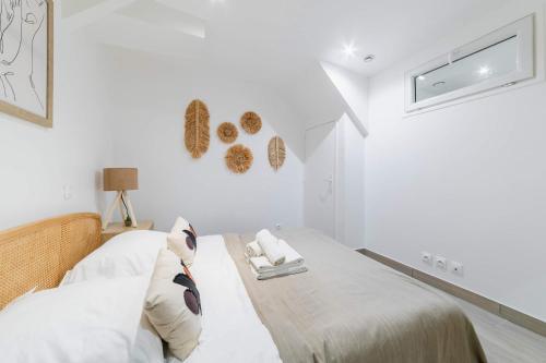 a white bedroom with a bed with white sheets and pillows at Les Lilas Appartement 1 chambre wifi et confort in Les Lilas