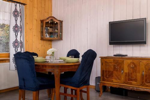 ein Esstisch mit blauen Stühlen und einem Fernseher in der Unterkunft Spacious House For Families Szczyrk in the Mountains by Noclegi Renters in Szczyrk