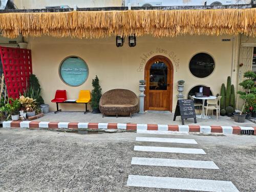 a house with a straw roof and a table and chairs at Bangkhunnon Station Hostel in Sathani Thon Buri