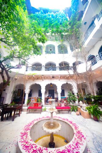 a fountain in the middle of a building with pink flowers at Inn Seventh Heaven in Pushkar