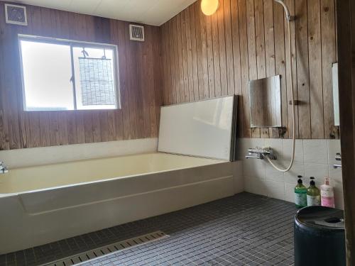 a bathroom with a bath tub and a window at Ryokan Kume Himawari Sou in Sakaide