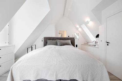 een witte slaapkamer met een groot bed met witte muren bij Sylter Strandholz in Westerland