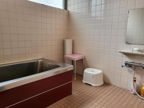 a bathroom with a tub and a pink toilet at Ryokan Kume Himawari Sou in Sakaide