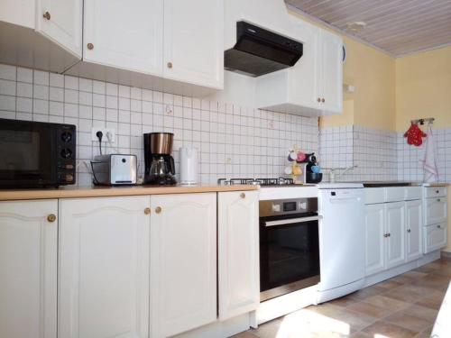 ValadyにあるGîte de Goutrensの白いキャビネットとコンロ付きオーブンを備えたキッチン