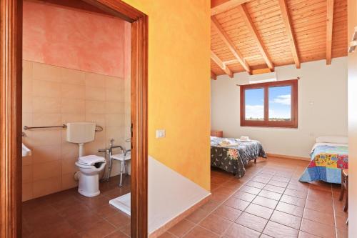 a bathroom with a toilet and a bed in a room at Agriturismo Su Nuratolu in Sagama