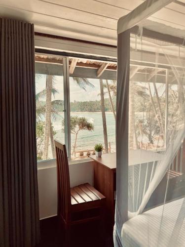 a bedroom with a bed and a desk and a window at Surf Home Stay Hiriketiya in Hiriketiya