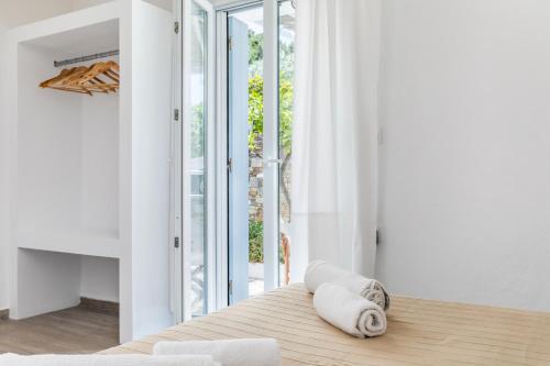 a bedroom with white walls and a bed with towels on it at Milia Beach Apartments in Paralia Milia
