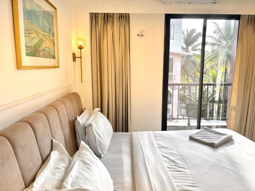 una habitación de hotel con una cama y una ventana en Beige 1BHK Family Retreat - Gym, Pool Access - Near Candolim Beach, en Candolim