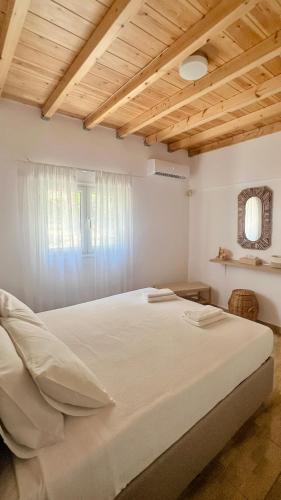 a bedroom with a large white bed with a wooden ceiling at Vive Mar Paxos in Gaios
