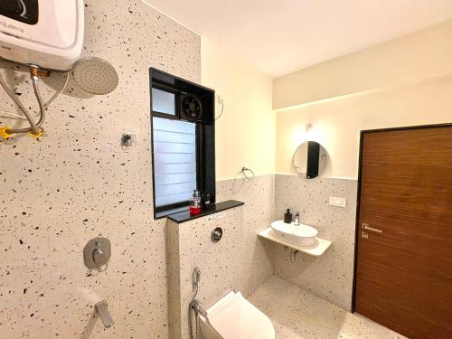 Un baño con inodoro, lavabo y ventana. en Beige 1BHK Family Retreat - Gym, Pool Access - Near Candolim Beach, en Candolim