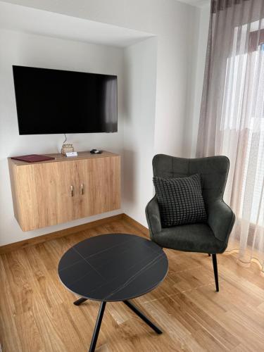 a living room with a chair and a table and a tv at Gasthof Kocherbähnle GmbH in Gaildorf