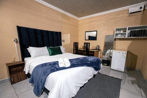 - une chambre avec un grand lit et des chaussons dans l'établissement 166 Klipspringer Guest house, à Germiston