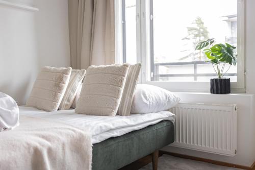 a bedroom with a bed with white pillows and a window at Modern Aurora Apartment with Sauna - Rovaniemi by Book Lapland in Rovaniemi