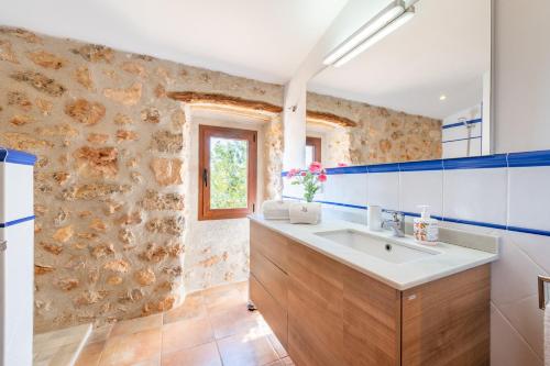 a bathroom with a sink and a stone wall at Els Garroverets in Binissalem