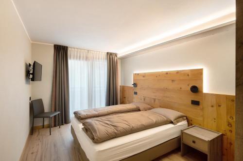 een slaapkamer met een bed met een houten muur bij Sun Mountain Planet Suite House in Livigno