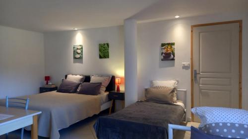 a bedroom with two beds and a table and a chair at Gîte Chez Gwen et Flo avec Jardin in Cholet