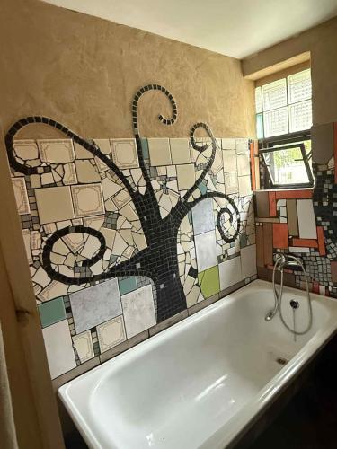 a bathroom with a bath tub with a mosaic wall at Cozy cottage in the heart of Čičmany in Čičmany
