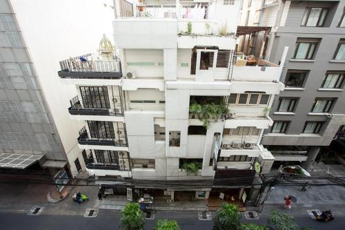 a tall white building with plants on it at Qilombo Hostel Silom in Bangkok