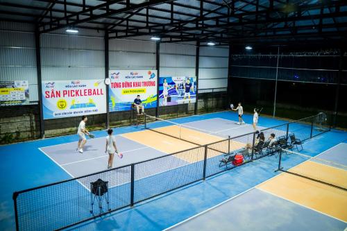 a group of people playing tennis on a tennis court at Kovie Hoa Lac Xanh Resort in Nam Giao