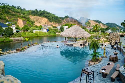 a swimming pool in a resort with a river at Kovie Hoa Lac Xanh Resort in Nam Giao
