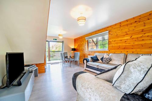 a living room with a couch and a flat screen tv at La Fortuna Lodges in Stirling