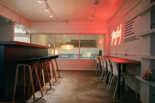 Una barra con taburetes en un restaurante con iluminación roja en Qilombo Hostel Silom, en Bangkok