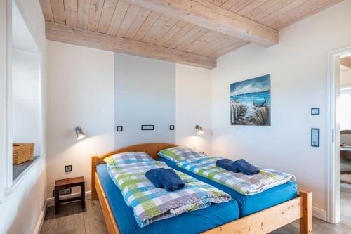two beds in a bedroom with white walls and wooden ceilings at Lüthjes Friesenhaus in Rodenäs