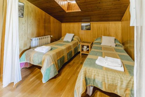 two beds in a room with wooden walls and wooden floors at Valle De Juarros in San Adrián de Juarros