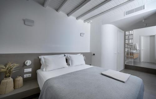 a white bedroom with a large bed with white pillows at ANOTERRA VILLAS -Anassa in Ambelas