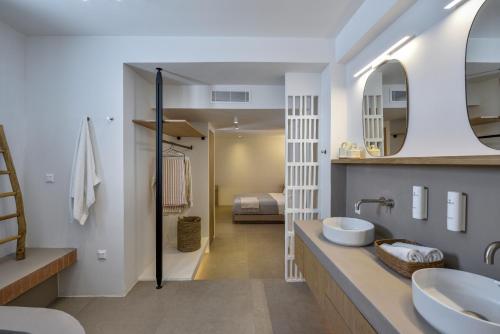 a bathroom with two sinks and a bedroom at ANOTERRA VILLAS -Anassa in Ambelas