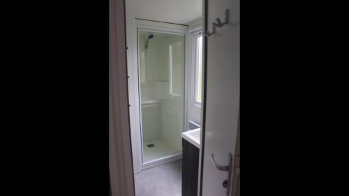ein Badezimmer mit Dusche mit Spiegel und Waschbecken in der Unterkunft Bungalow Camping 4 à 8 personnes in Les Mathes