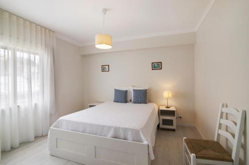 ein weißes Schlafzimmer mit einem weißen Bett und einem Fenster in der Unterkunft Apartamento Jardins da Falésia in Albufeira