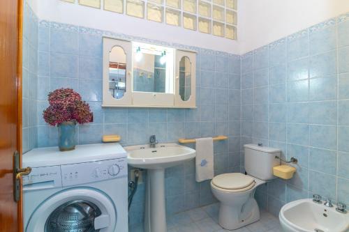 a blue tiled bathroom with a toilet and a sink at Rena Bianca Magico Trilo Rosso in Santa Teresa Gallura