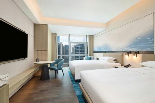 a hotel room with two beds and a flat screen tv at Courtyard by Marriott Zhuhai in Zhuhai