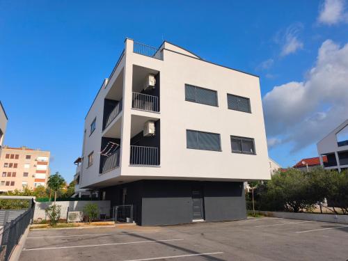 a white building with a parking lot at DiViNI apartment in Zadar