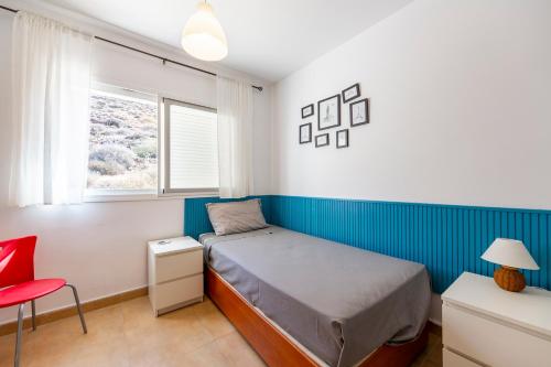 1 dormitorio pequeño con 1 cama y 1 silla roja en Casa Rous, en Presillas Bajas