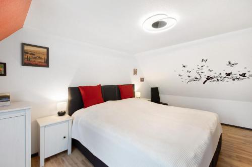 a bedroom with a white bed and red pillows at Ferienhaus Koch in Bad Harzburg