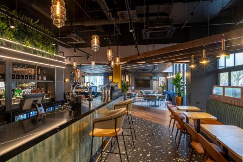 a bar with wooden tables and chairs in a restaurant at Holiday Inn Derby Riverlights by IHG in Derby