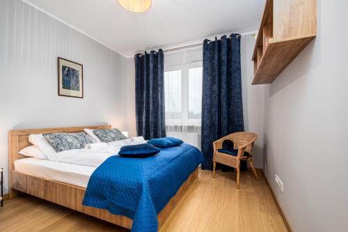 ein Schlafzimmer mit einem Bett mit einer blauen Decke darauf in der Unterkunft Szeligowska, Sun & Snow in Warschau