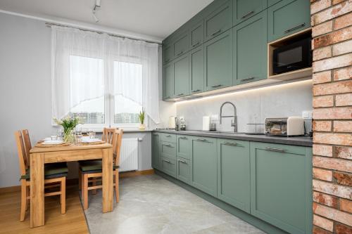 eine Küche mit grünen Schränken und einem Holztisch in der Unterkunft Szeligowska, Sun & Snow in Warschau